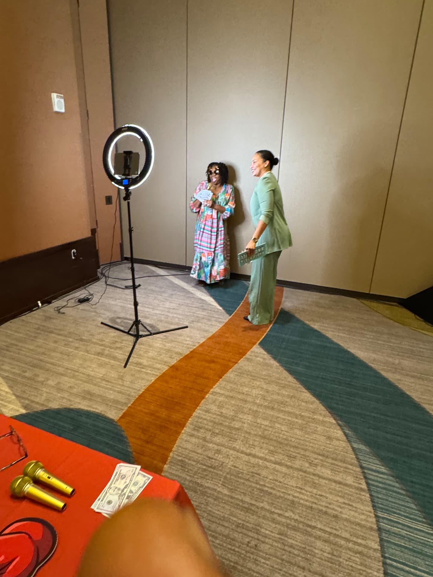 Two women posing with props in front of a ring light at the reception